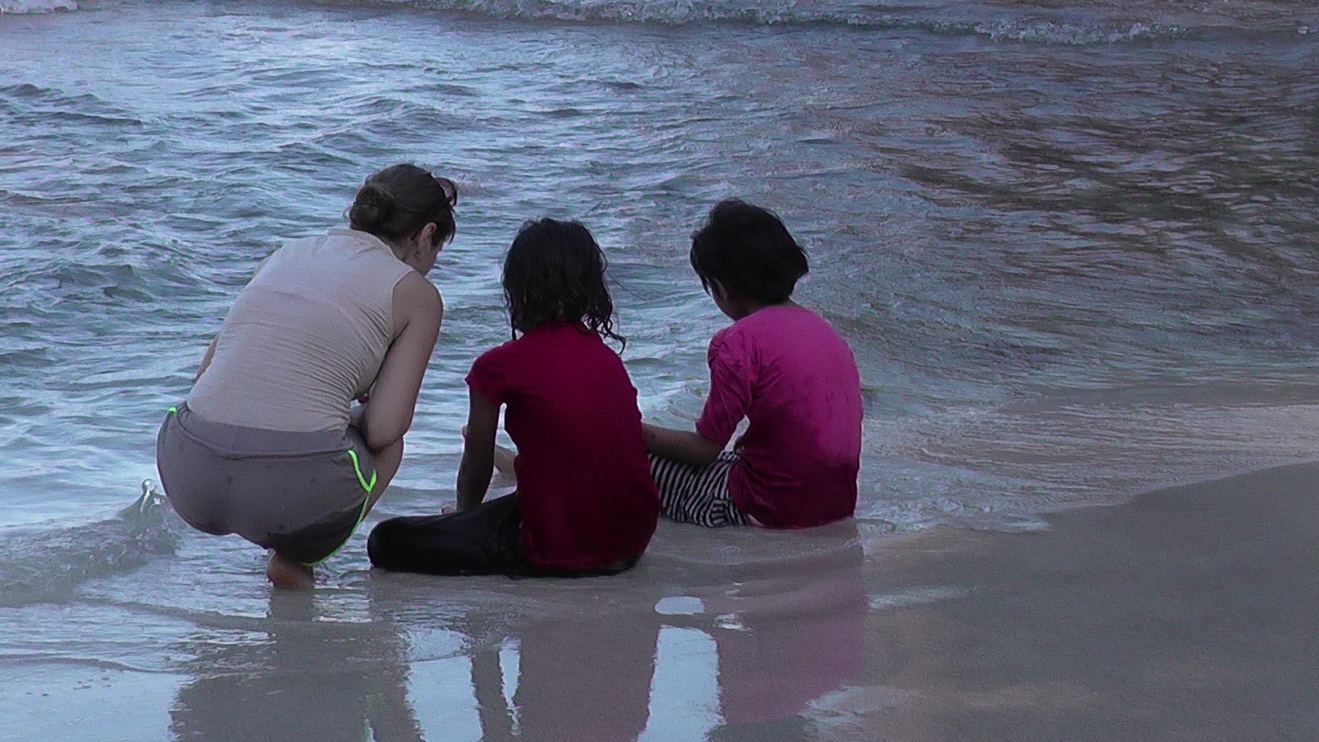 Voluntärin mit Kindern am Strand