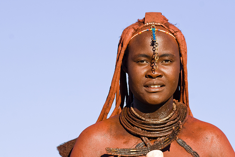 Eine stolze Frau des Himba-Volkes. Um sich vor der Sonne zu schützen, reiben sich die Himba täglich mit Ockerpaste ein, eine Mixtur aus zerstoßene roten Steinbrocken und Kuhfett.